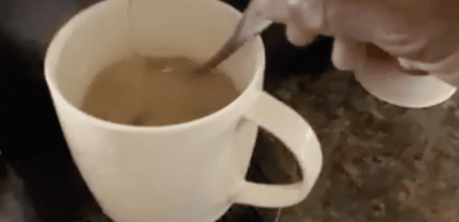 Stirring coffee in a white mug.
